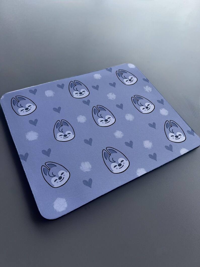 May include: A blue mouse mat with a repeating pattern of a cartoon animal with hearts and white dots.