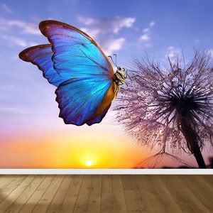May include: A blue butterfly with iridescent wings perched on a dandelion seed head with dew drops. The background is a colourful sunset sky.