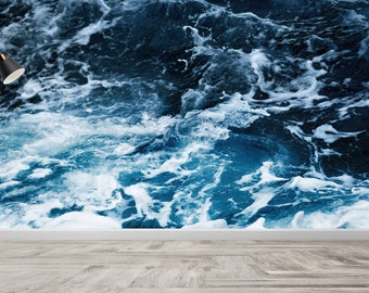 May include: A black floor lamp with a white lampshade stands in front of a wall mural depicting a close-up of blue ocean waves with white foam.