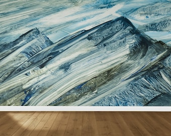 May include: Abstract painting with blue, white, and gray brushstrokes creating a textured mountain-like pattern. The painting is displayed on a wall above a wooden floor.