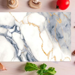 May include: A rectangular marble cutting board with a white base, gray veining, and gold accents. The board is surrounded by fresh ingredients, including a red tomato, mushrooms, garlic cloves, and basil leaves.