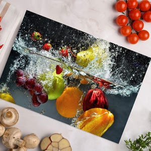 May include: A vibrant image of fruits submerged in water, including grapes, strawberries, pears, and oranges. Red chili peppers, cherry tomatoes, mushrooms, and garlic cloves are arranged around the main image on a white surface.