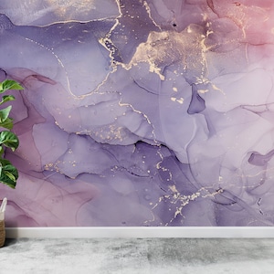 May include: A plant in a woven basket sits in front of a wall with an abstract purple and pink marbled design with gold accents.