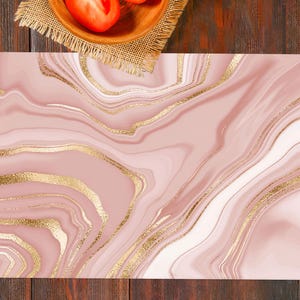 Könnte beinhalten: Ein rechteckiges, abstraktes Design mit rosa Marmormuster und goldenen Akzenten. Das Design hat ein fließendes, organisches Aussehen, wobei die goldenen Adern einen Hauch von Luxus verleihen. Das Bild ist vor einem dunklen Holzgrund platziert.