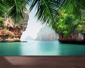 May include: A scenic view of a tropical bay with lush green foliage, rocky cliffs, and turquoise water. A wooden surface is in the foreground, creating a platform for displaying products.