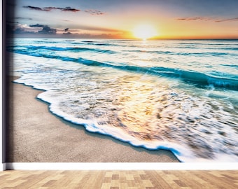May include: A scenic beach scene with a golden sunrise over the ocean. The waves are crashing on the sandy shore, creating a beautiful and tranquil atmosphere.