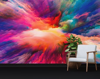 May include: Abstract art print featuring a colorful explosion of paint in shades of pink, purple, blue, orange, and yellow. The print is displayed on a wall with a white chair and a potted plant in front of it.