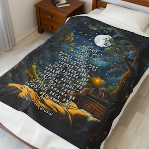 May include: A soft, printed blanket featuring a nighttime forest scene with a full moon and stars. The blanket has a quote from Ursula K. Le Guin in white text. The color palette includes blues, greens, and yellows.