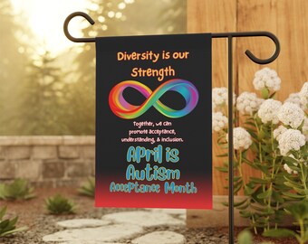 May include: A black garden flag with the text "Diversity is our Strength" and "April is Autism Acceptance Month." The flag features a colorful infinity symbol and is displayed outdoors.