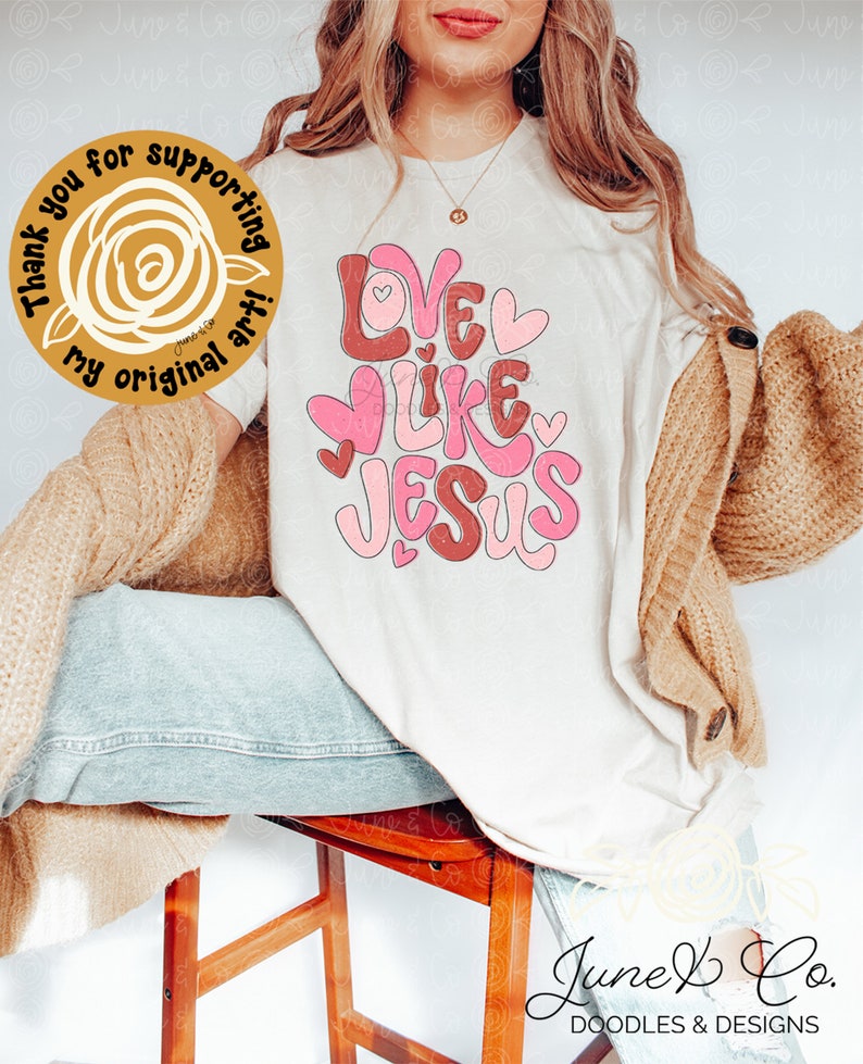 May include: White t-shirt with the text "Love Like Jesus" in pink and brown lettering with hearts. The text is in a playful, hand-drawn style.