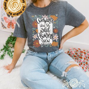 May include: A gray t-shirt with a floral design and the text "Consider how the wild flowers grow Luke 12:27-28".