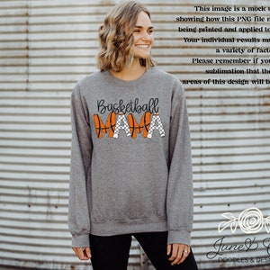 May include: Grey sweatshirt with the text "Basketball Mama" in black lettering. The letters are decorated with orange basketballs and black nets.