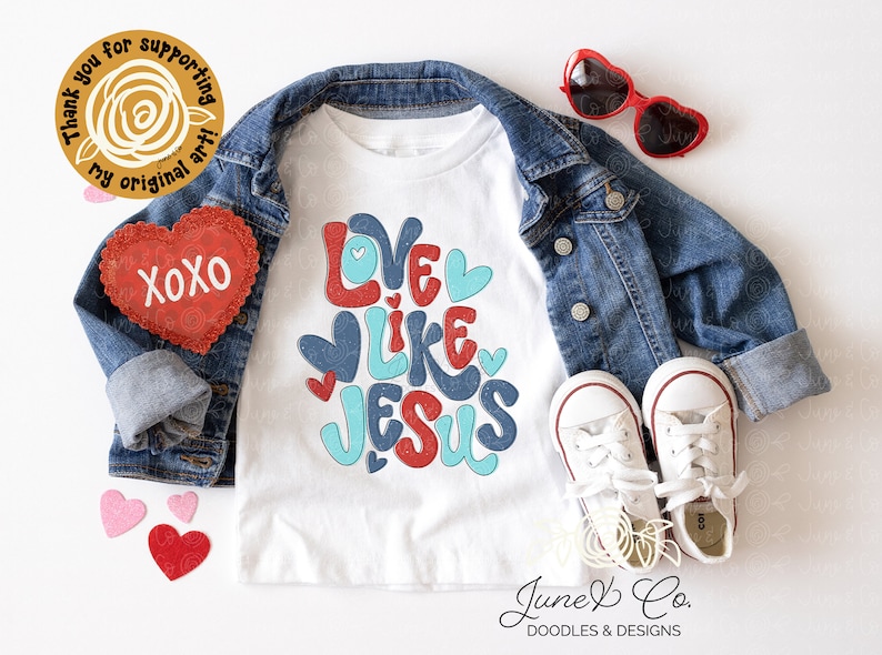 Peut inclure: T-shirt blanc pour enfant avec le texte "Love Like Jesus" en lettres rouges, bleues et turquoise avec des c&oelig;urs. Le t-shirt est pr&eacute;sent&eacute; sur un fond blanc avec une veste en jean, des lunettes de soleil en forme de c&oelig;ur rouges et des c&oelig;urs en feutre rouge.