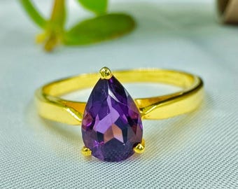 May include: A gold ring with a pear-shaped amethyst gemstone.