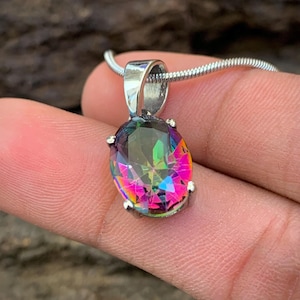May include: A silver chain necklace with a large oval-shaped iridescent gemstone pendant. The gemstone is a mix of pink, green, and blue.