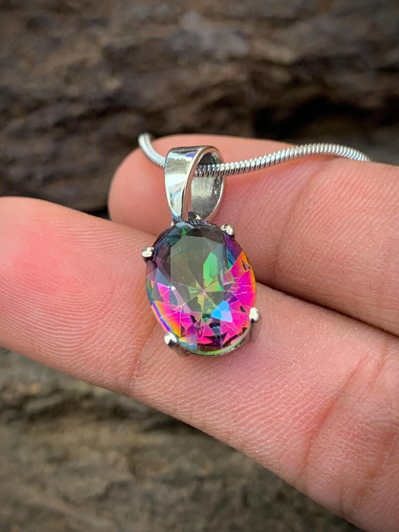 May include: A silver chain necklace with a large oval-shaped iridescent gemstone pendant. The gemstone is a mix of pink, green, and blue.