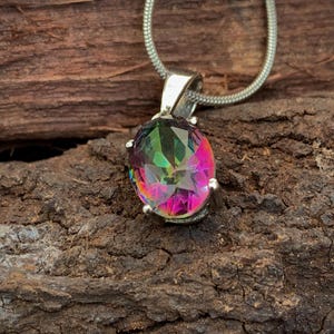 May include: A silver chain necklace with a pendant featuring a large oval-shaped iridescent gemstone. The gemstone has a rainbow of colors, including pink, green, and blue.