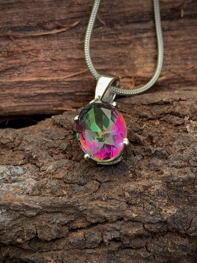 May include: A silver chain necklace with a pendant featuring a large oval-shaped iridescent gemstone. The gemstone has a rainbow of colors, including pink, green, and blue.