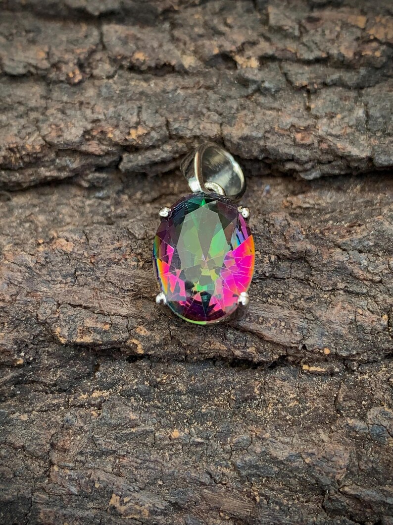 May include: A silver pendant with a large oval-shaped iridescent gemstone. The gemstone has a rainbow of colors, including red, pink, green, and blue.