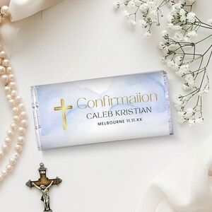 May include: A white and blue watercolor design with a gold cross and the text "Confirmation Caleb Kristian Melbourne 11.11.XX".