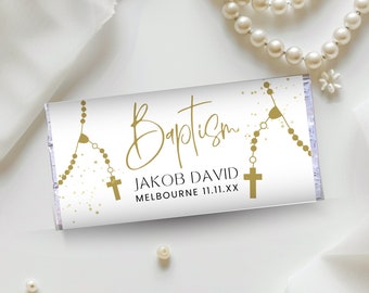 May include: White chocolate bar wrapper with gold foil accents. The wrapper features a gold rosary with a cross and the text "Baptism" in gold script. The text "Jakob David" and "Melbourne 11.11.XX" is printed in black.