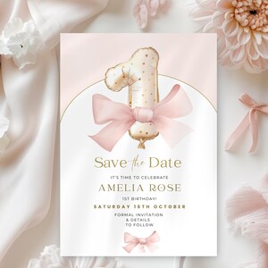 May include: A pink and gold save the date card with a gold balloon shaped like the number one with pink polka dots. The balloon is tied with a pink ribbon bow. The text on the card reads "Save the Date", "It's time to celebrate", "Amelia Rose", "1st Birthday!", "Saturday 16th October", "Formal Invitation & Details to Follow".