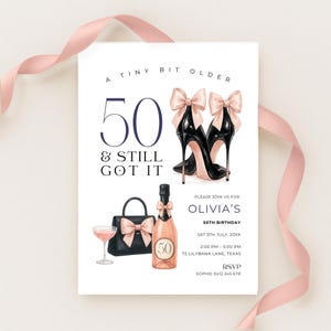Puede incluir: Una tarjeta de invitación blanca con el texto "A TINY BIT OLDER 50 & STILL GOT IT." La tarjeta presenta ilustraciones de tacones altos negros, un bolso, una botella de champán y una copa de bebida rosa. Una cinta rosa está drapeada sobre la tarjeta.