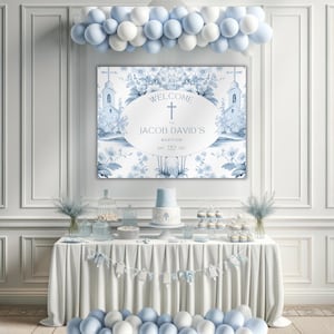 May include: A baptism party scene featuring a table with a white cloth, a cake, cupcakes, and other refreshments. A sign reading "Welcome to Jacob David's Baptism" is displayed above, complemented by blue and white balloons. The date is also displayed.