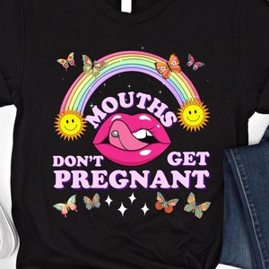 May include: Black t-shirt with a graphic design featuring a pink mouth with a tongue piercing, a rainbow, butterflies, and the text "MOUTHS DON'T GET PREGNANT". The design includes two smiling suns.