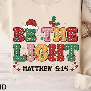 Be The Light Christmas Sweatshirt Christmas Shirt for Women Religious Christmas Sweater Bible Verse Hoodie Christian Holiday Believe T-Shirt