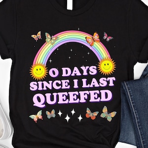 May include: Black t-shirt with a rainbow, butterflies, and the text "0 Days Since I Last Queefed".