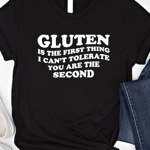 May include: Black t-shirt with white text that reads "Gluten is the first thing I can't tolerate you are the second".