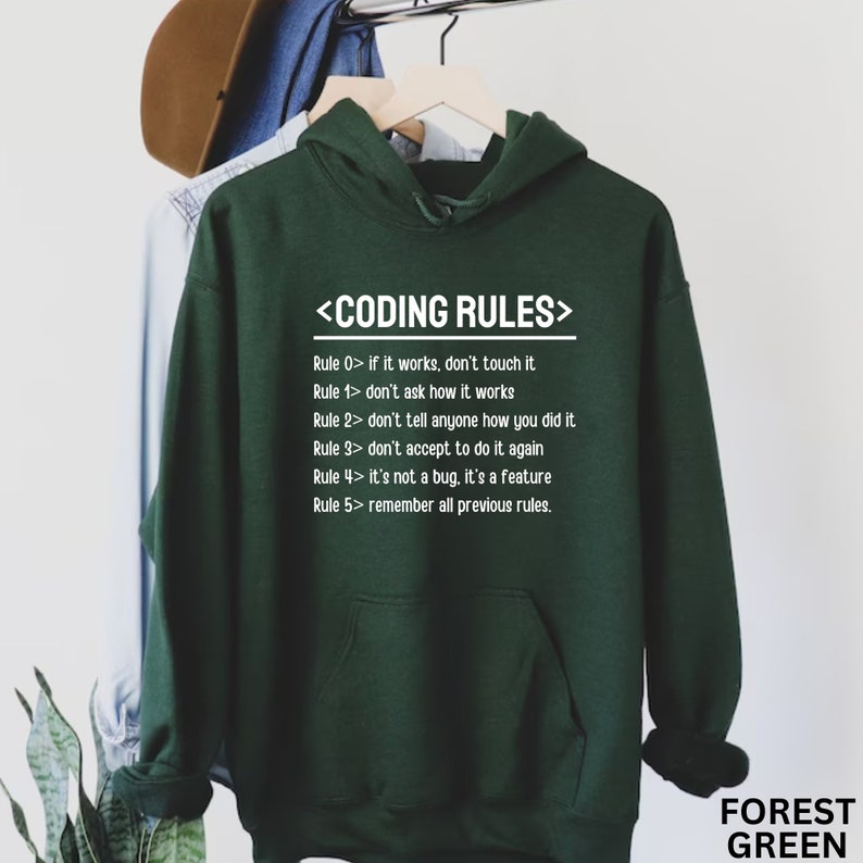 Puede incluir: Una sudadera con capucha verde oscuro con una impresi&oacute;n blanca que dice "<CODING RULES>" y enumera cinco reglas para la codificaci&oacute;n. La sudadera tiene una capucha con cord&oacute;n y un bolsillo canguro.