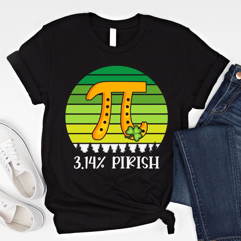 Puede incluir: Camiseta negra con un gr&aacute;fico del s&iacute;mbolo Pi en naranja, sobre un fondo a rayas verdes y amarillas. El texto "3.14% PIRISH" est&aacute; impreso debajo. Un tr&eacute;bol est&aacute; incluido en el dise&ntilde;o.