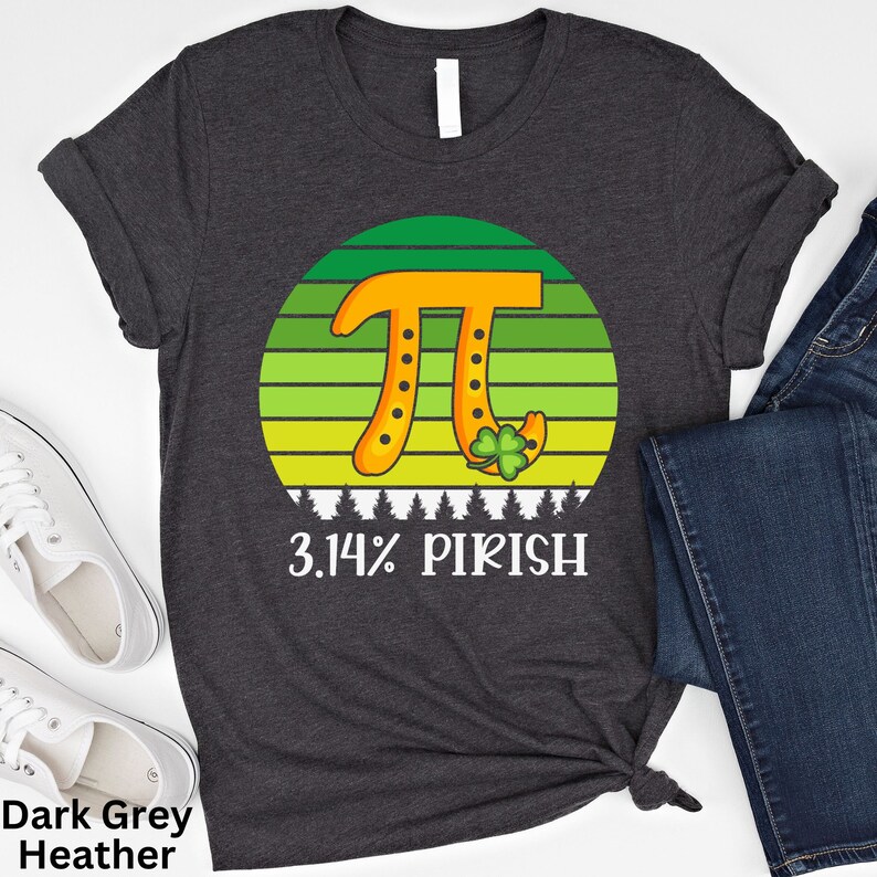 Puede incluir: Camiseta gris oscuro jaspeado con un gr&aacute;fico del s&iacute;mbolo Pi naranja sobre un fondo a rayas verdes y amarillas. El texto "3.14% PIRISH" est&aacute; debajo. La camiseta se combina con vaqueros y zapatillas blancas.