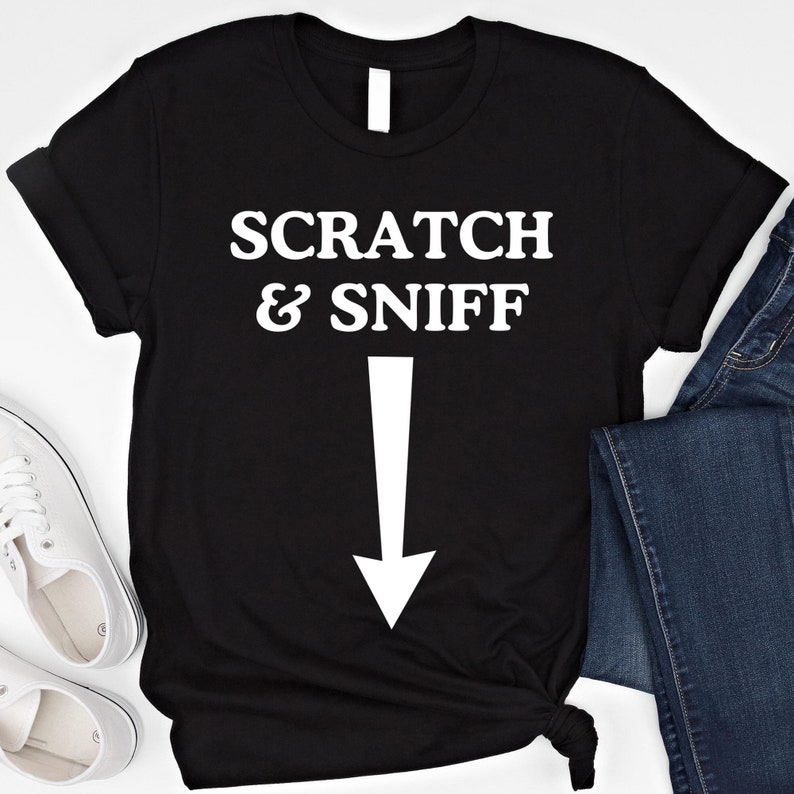 May include: Black t-shirt with white text that reads "SCRATCH & SNIFF" with a white arrow pointing down.