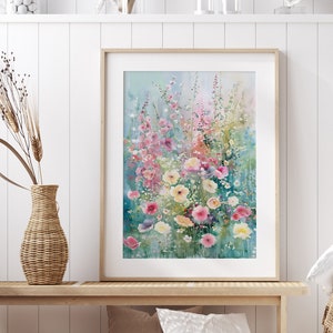 Könnte beinhalten: Ein gerahmtes Aquarellbild mit einem Blumenarrangement in Rosa, Weiß und Gelb. Das Bild hängt an einer weißen Wand über einer Holzbank.