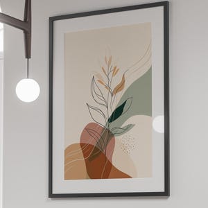 May include: A framed abstract art print featuring a botanical design with neutral tones of beige, brown, and green. The artwork is displayed on a white wall above a black dining table with matching black chairs.
