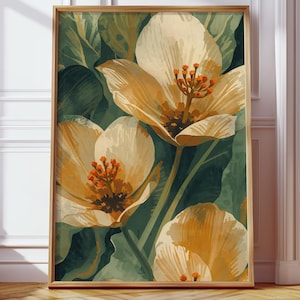 以下が含まれることがあります： 大きなクリーム色の花とオレンジ色の中心、緑の葉を描いた水彩画の額入りアートプリント。 金色のフレームに入れられたアートワークは、木製の床に置かれています。