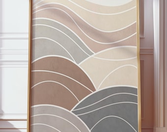 May include: A framed art print with an abstract design of layered, curved shapes in brown, beige, and grey. The artwork is in a gold frame, set against a white wall and wooden floor. The print's dimensions are not visible.