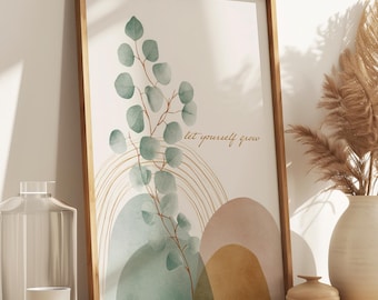 May include: A framed art print with a botanical design featuring eucalyptus leaves and the text "let yourself grow." The artwork is in a wooden frame and is displayed on a wooden cabinet. A vase with dried pampas grass and other decorative items are also present.