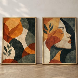 Könnte beinhalten: Zwei gerahmte Kunstdrucke mit abstrakten Designs. Einer zeigt ein geometrisches Muster in Orange, Beige und Dunkelgrün. Der andere zeigt ein Frauenprofil in Orange und Beige mit einem Zweig Blättern. Beide sind in goldenen Rahmen.
