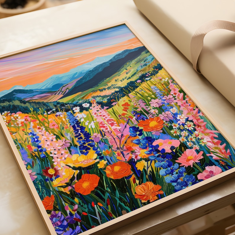 May include: A framed painting of a field of colorful wildflowers in front of a mountain range. The sky is a vibrant orange and blue.