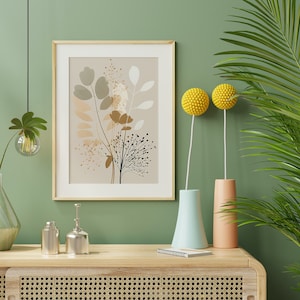 May include: A framed print of a botanical illustration with brown, beige, and white leaves and flowers on a beige background. The print is hanging on a sage green wall with a green plant in a light green vase, two yellow ball-shaped flowers in vases, and two silver decorative bottles on a light wood shelf.