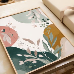 Può includere: Stampa artistica astratta in una cornice di legno. L'opera presenta un design botanico con forme rosa, verdi e dorate tenui. Delicate foglie ed elementi floreali sono sparsi su uno sfondo bianco, creando un'atmosfera moderna e organica.
