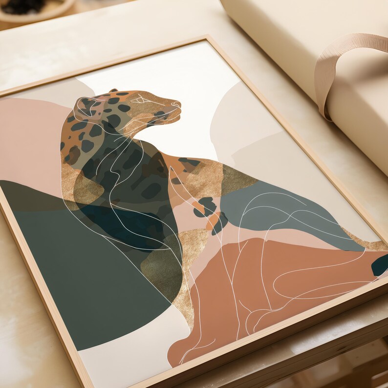 May include: Framed art print featuring an abstract illustration of a leopard. The artwork uses a palette of muted earth tones, including brown, beige, and green, with gold foil accents. The leopard is depicted in a stylized, minimalist form with white line details.