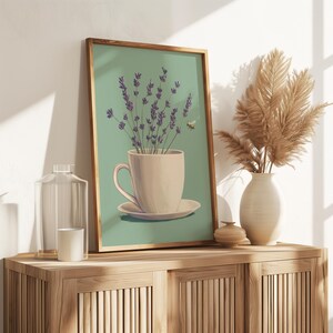 May include: A teal green framed print of a white teacup with lavender flowers inside. The teacup is on a white saucer and there is a small bee flying near the flowers.