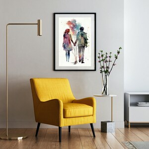 以下が含まれることがあります： 手をつないで歩いているカップルの水彩画。絵は黒の額縁で囲まれ、白い壁に飾られています。カップルはカラフルな背景にシルエットで描かれています。