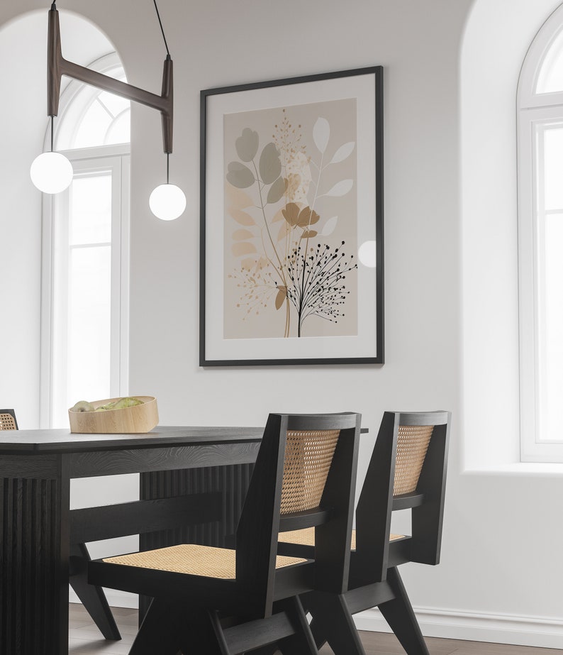 May include: A black dining table with two black chairs with woven cane seats. The table has a wood grain finish. A framed print with a beige background and abstract floral design hangs on the wall behind the table.