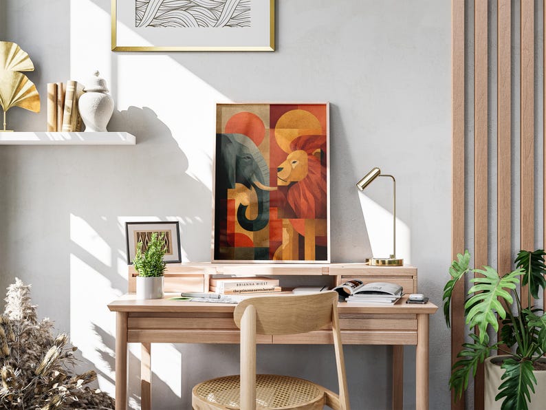 May include: A framed art print featuring an elephant and a lion in a geometric design with orange, red, and brown tones. The artwork is displayed on a wooden desk with a small lamp and a potted plant. The desk is in a room with a wooden accent wall.
